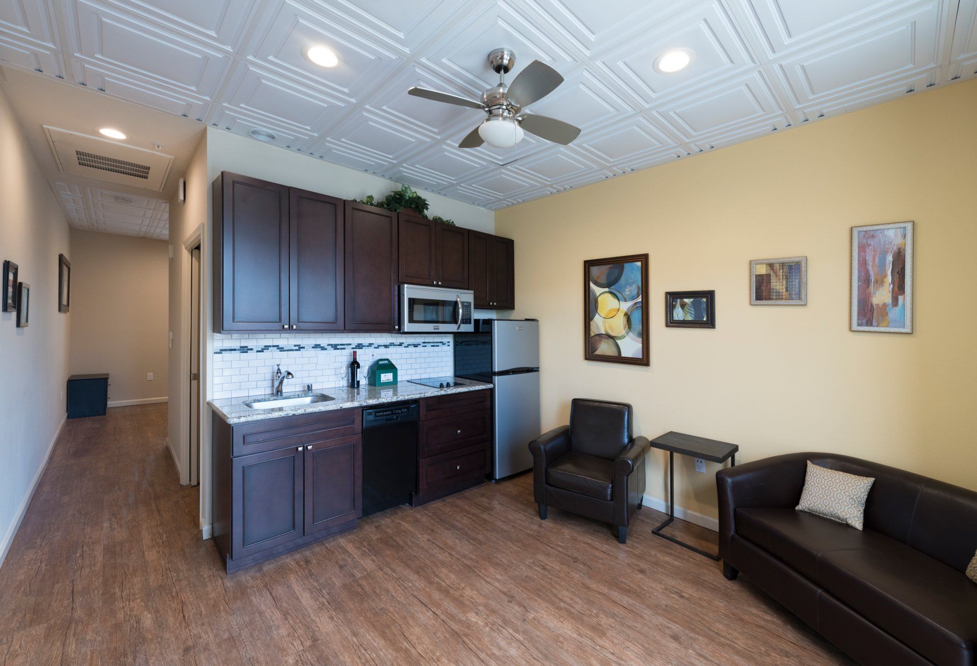 A living room with a couch, a chair and a kitchen