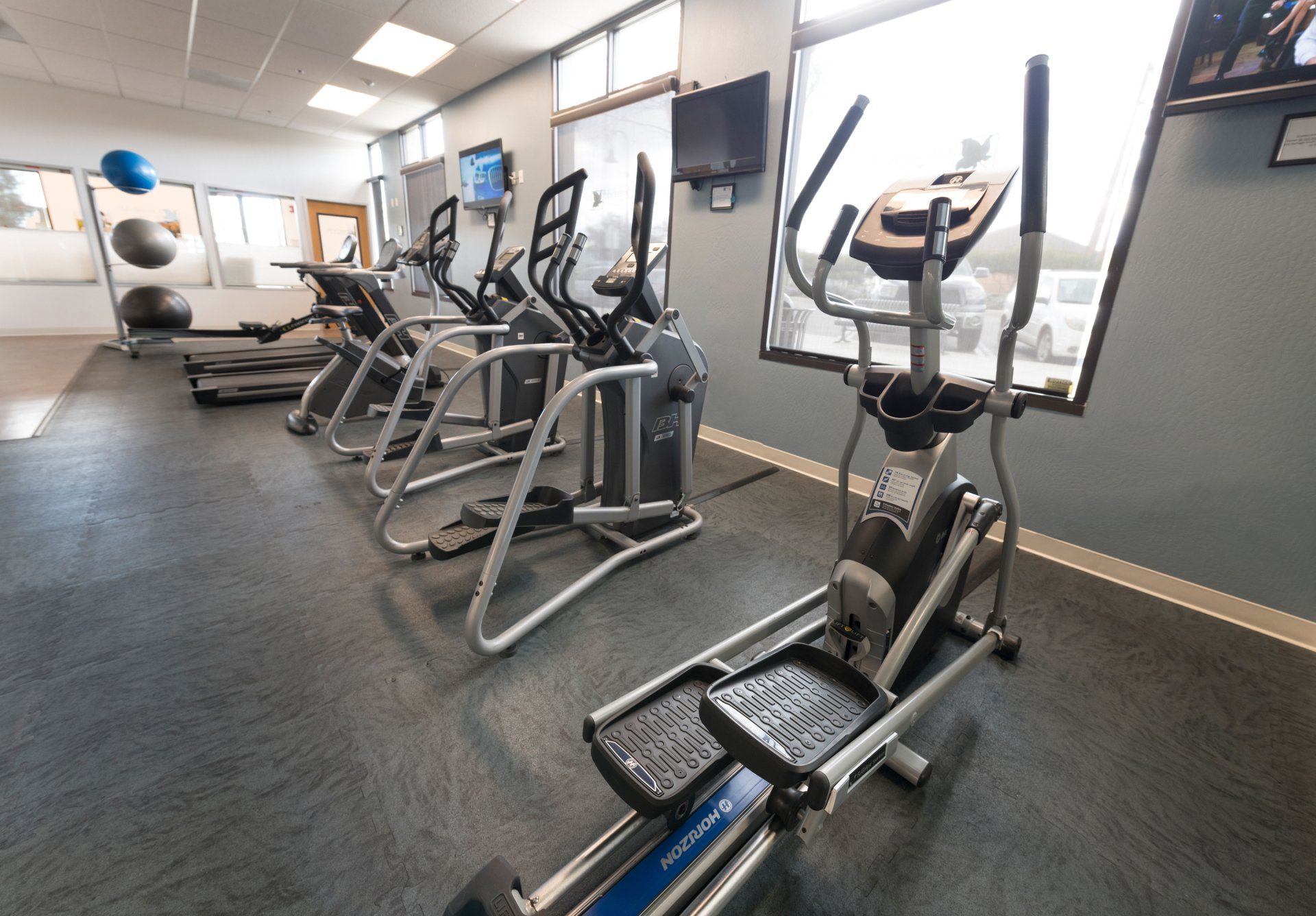 A row of treadmills and ellipticals in a gym