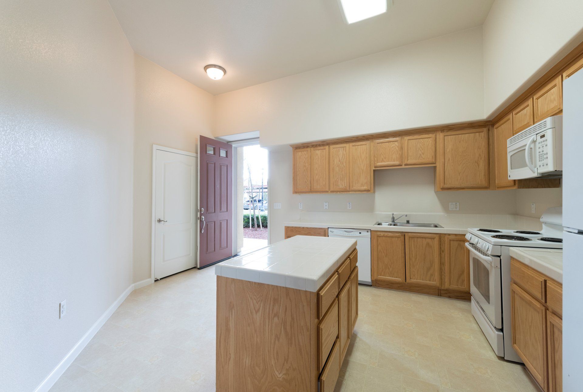 An empty kitchen with wooden cabinets and white appliances