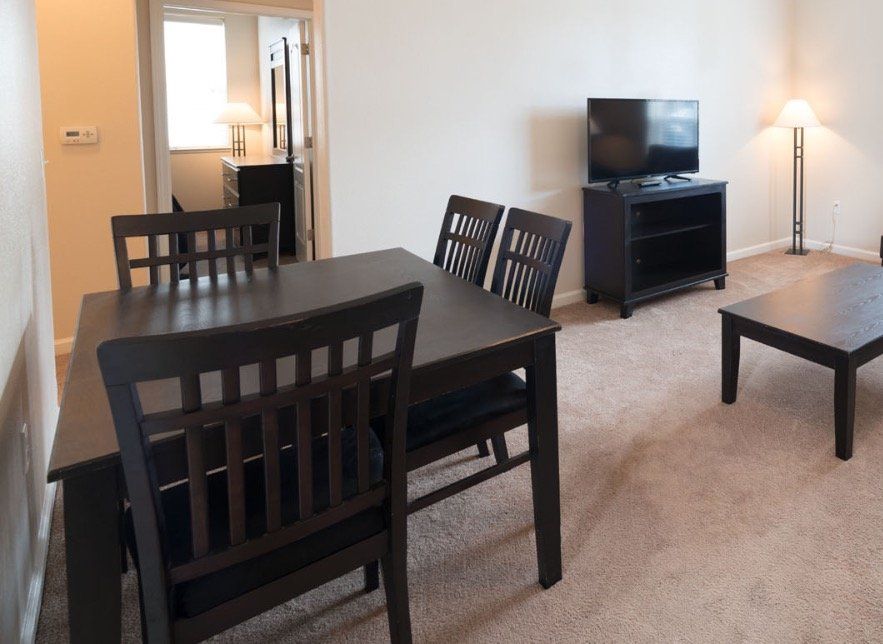 A living room with a table and chairs and a television
