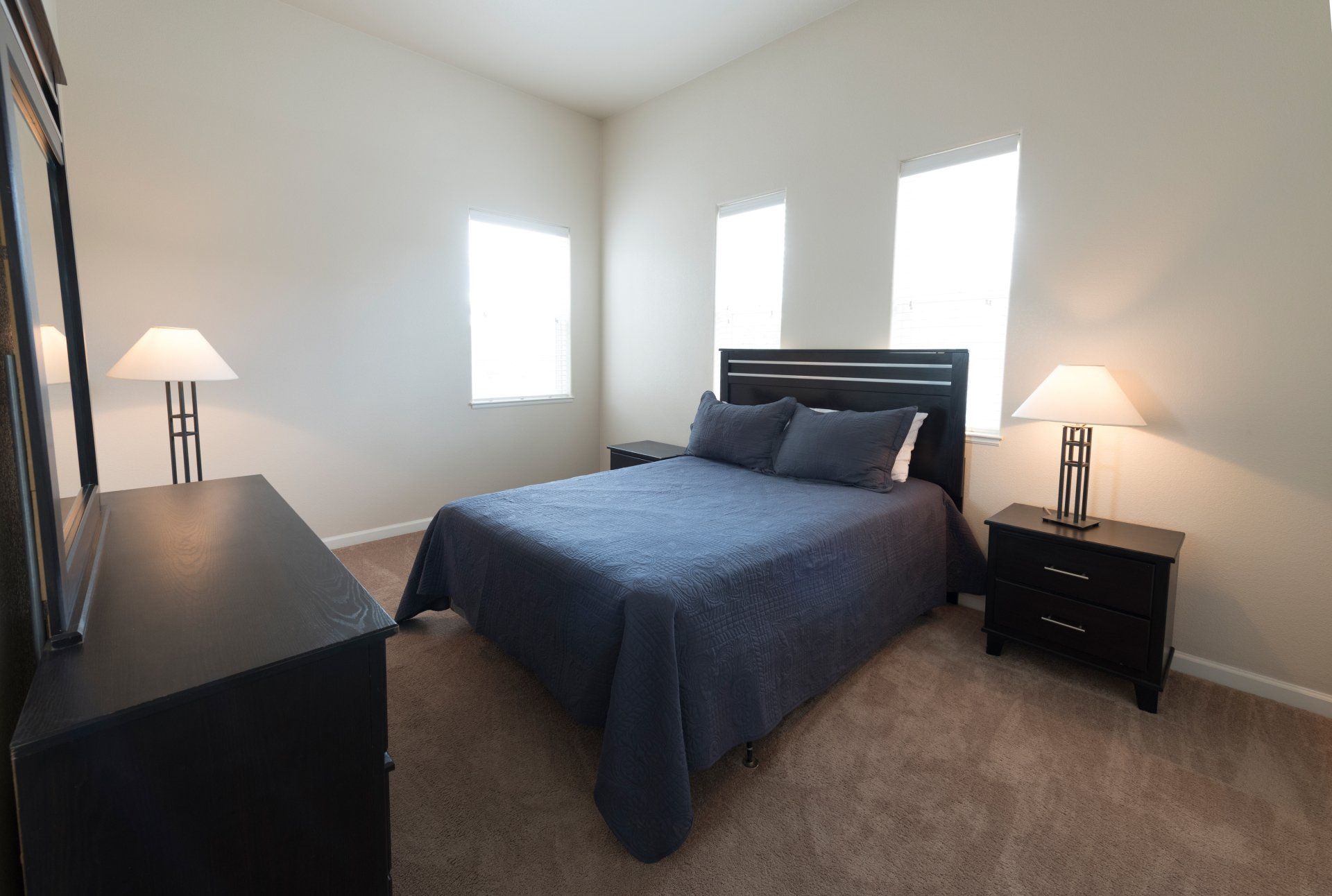 A bedroom with a bed dresser and two lamps