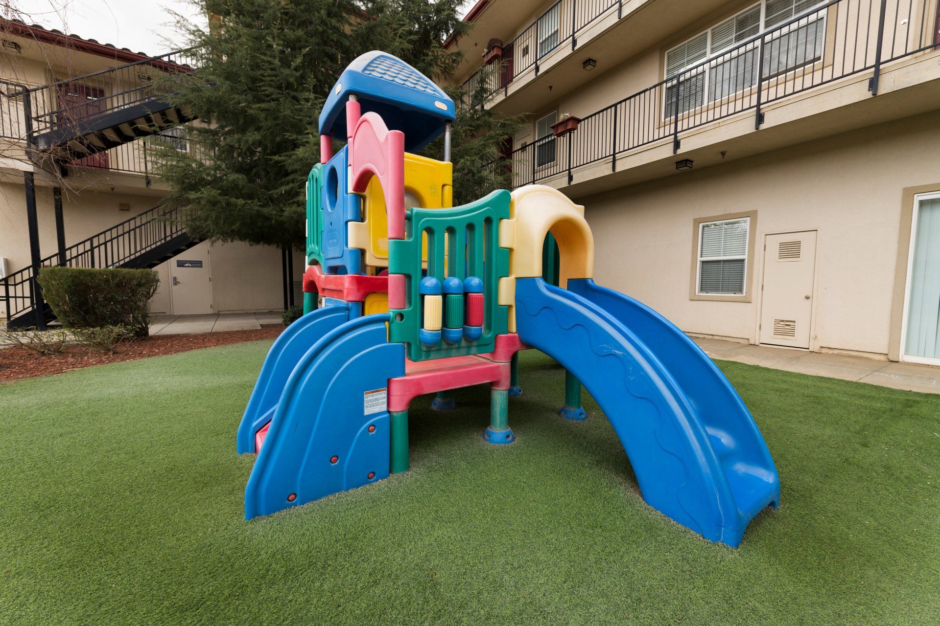 A playground with a slide and stairs in front of a building.
