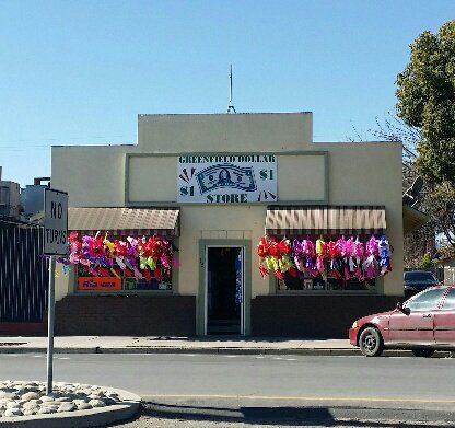 A greenfield dollar store with a red car parked in front