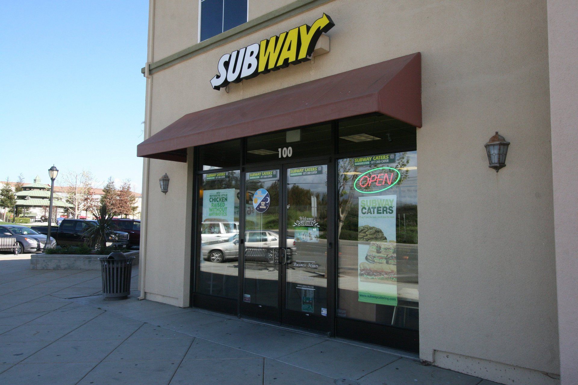 The outside of a subway restaurant with a red awning