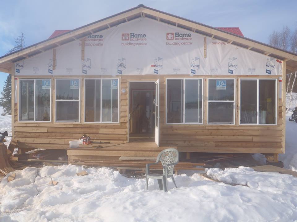 A house with a lot of windows is covered in snow