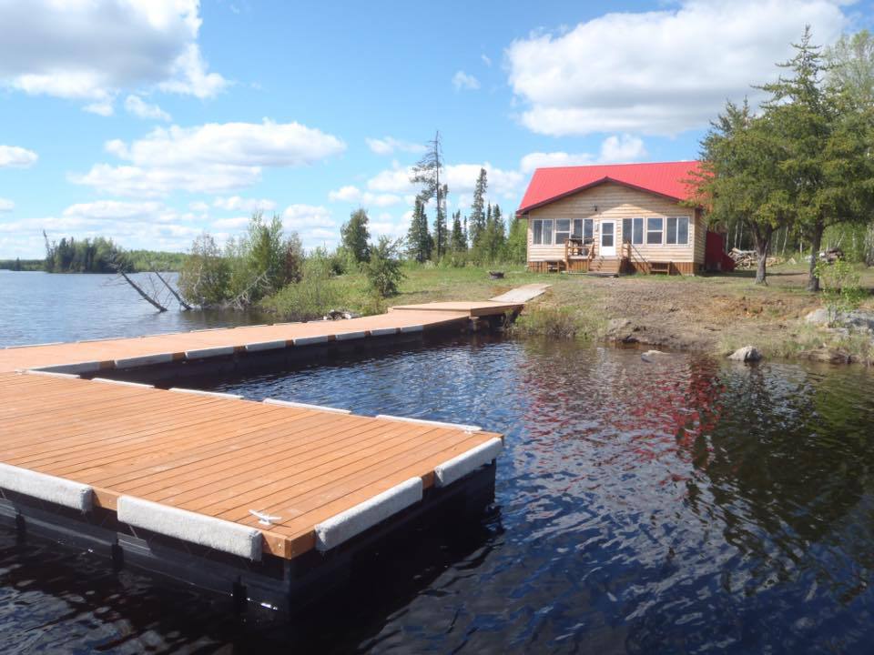 A house with a red roof sits on the shore of a lake