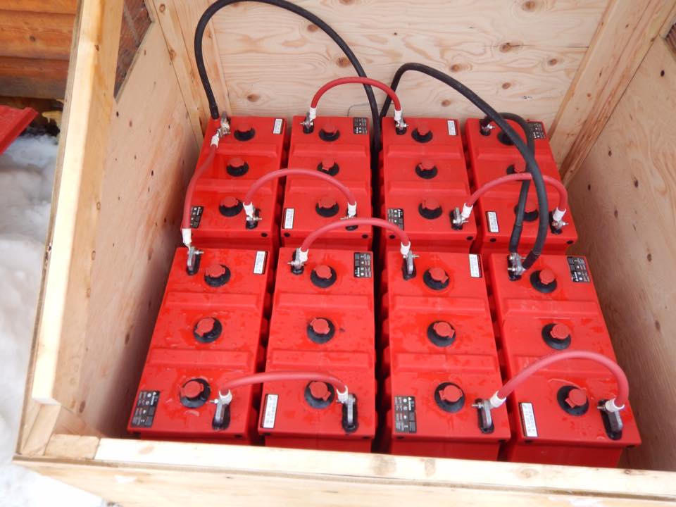 A bunch of red batteries in a wooden box