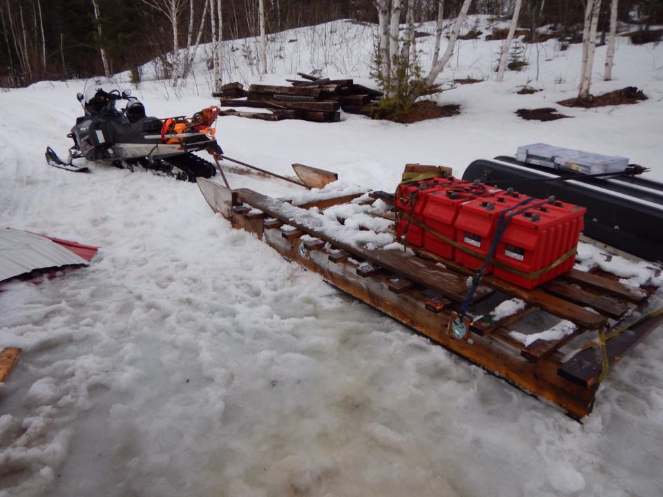 A snowmobile is parked in the snow next to a wooden sled