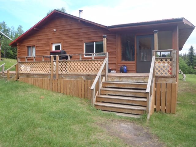 A wooden house with a large deck and stairs