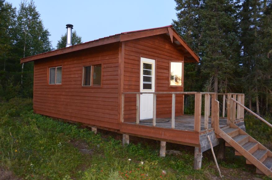 A small wooden house with a deck and stairs