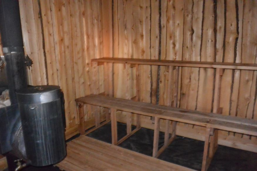 A wooden sauna with a wood stove and benches.