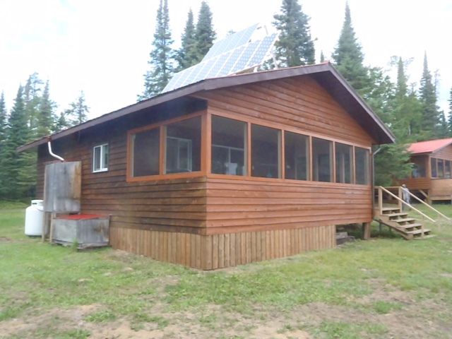 A small wooden house with a screened in porch and stairs