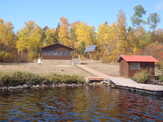 A house with a red roof is next to a body of water