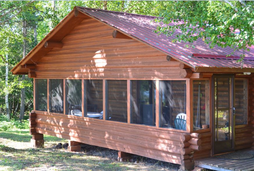 A log cabin with a screened in porch and a red roof