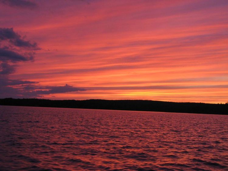 A sunset over a lake with a purple sky