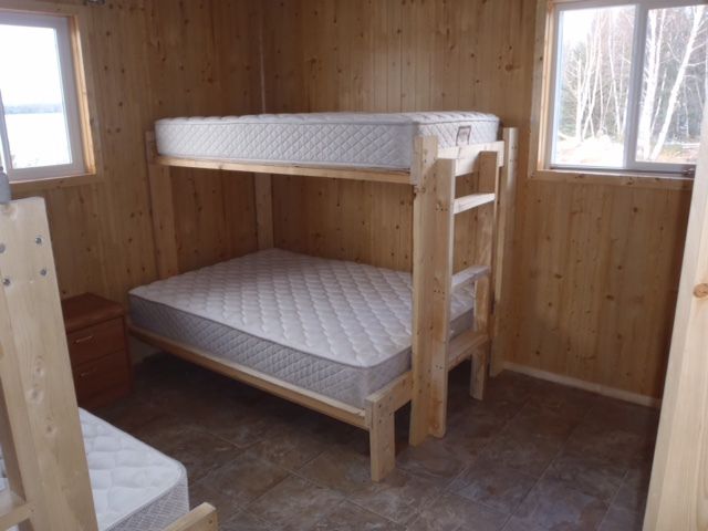 A bunk bed with two mattresses in a wooden room