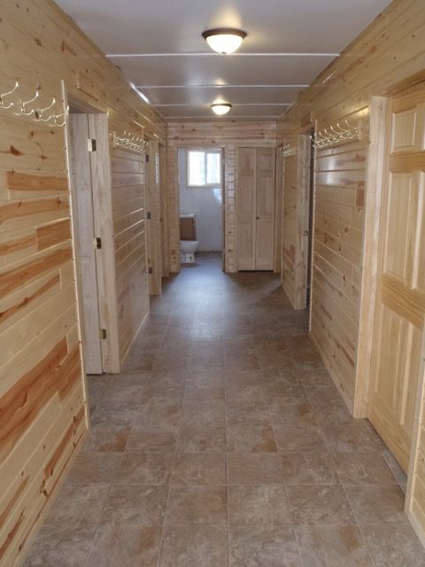 A hallway with wood paneling and tile floors leading to a bathroom