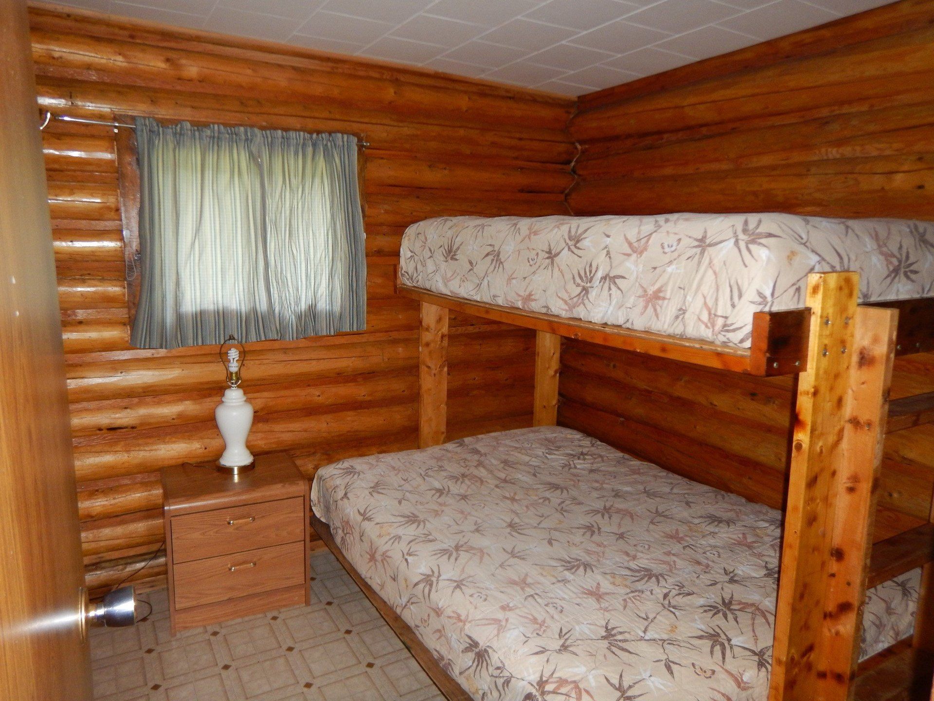 A bedroom in a log cabin with bunk beds and a nightstand