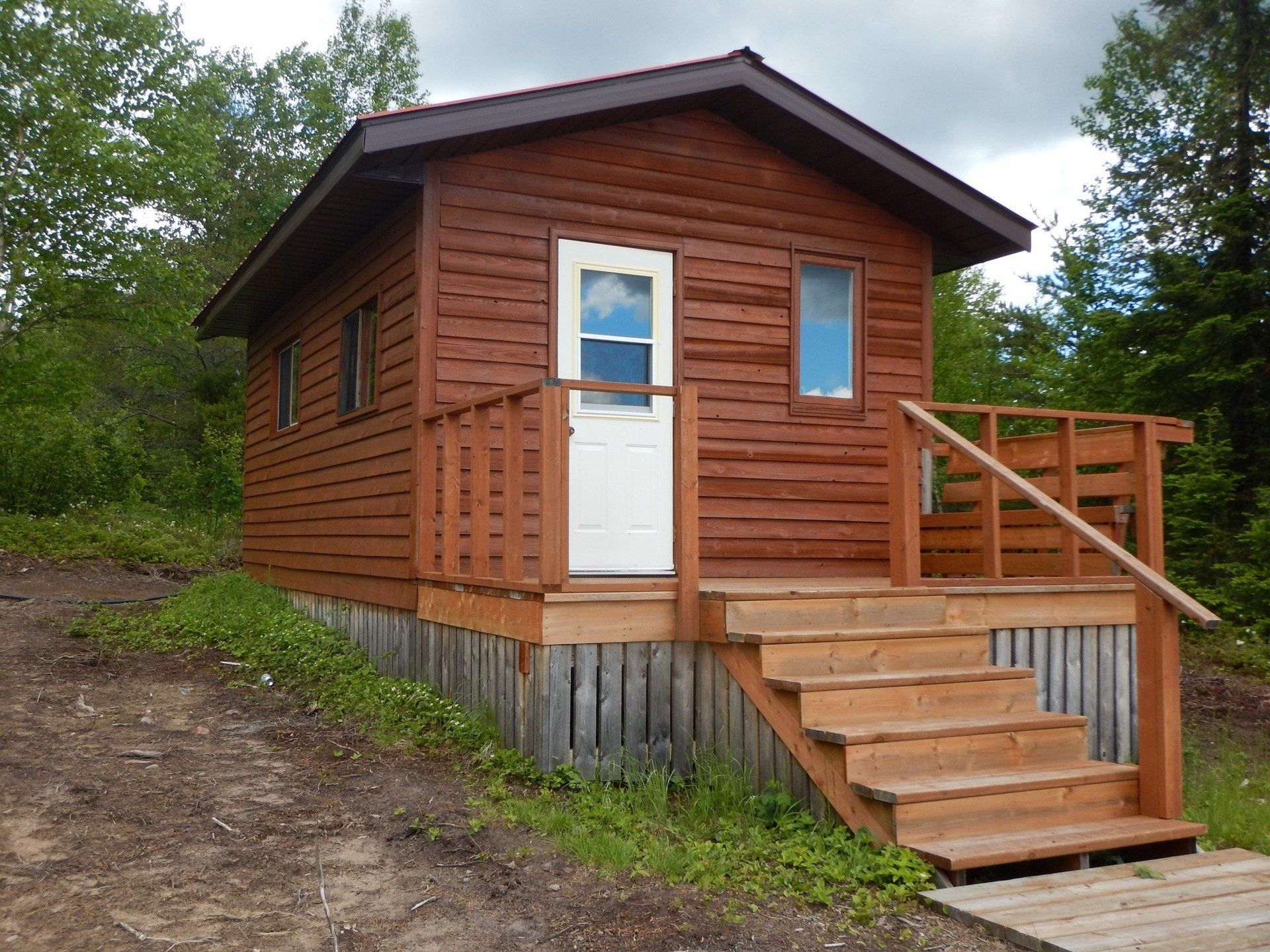 A small wooden cabin with stairs leading up to it