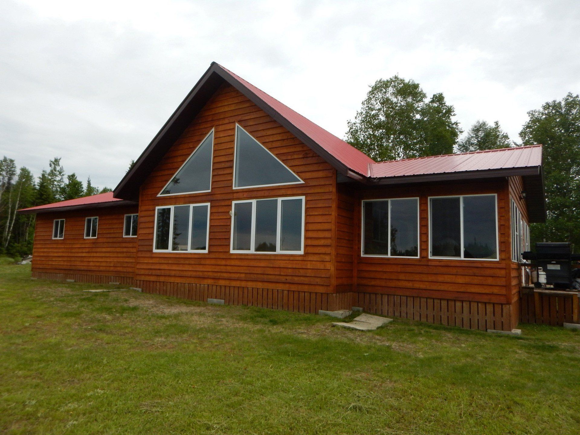A large log cabin with a red roof and lots of windows