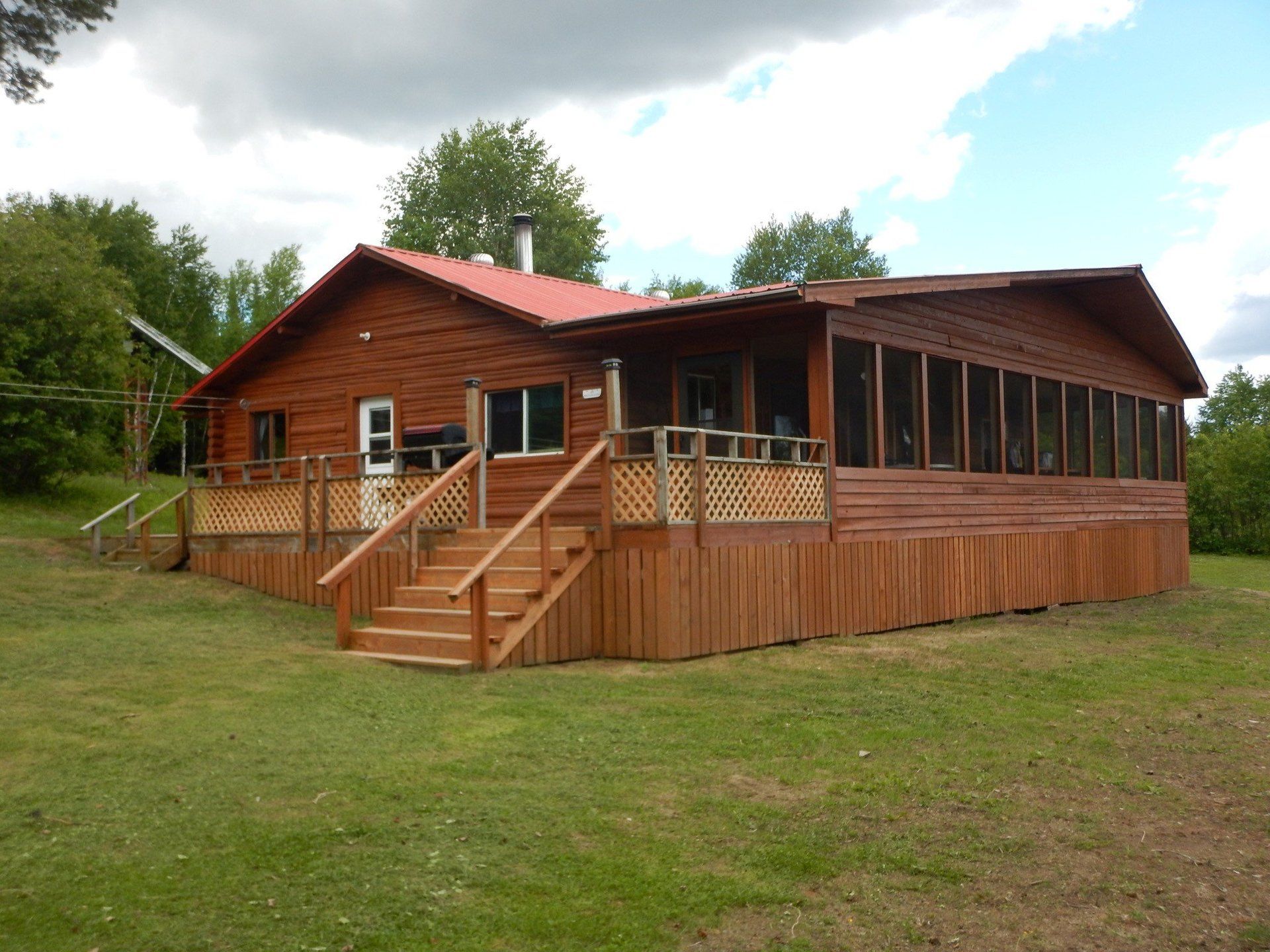 A log cabin with a screened in porch and stairs