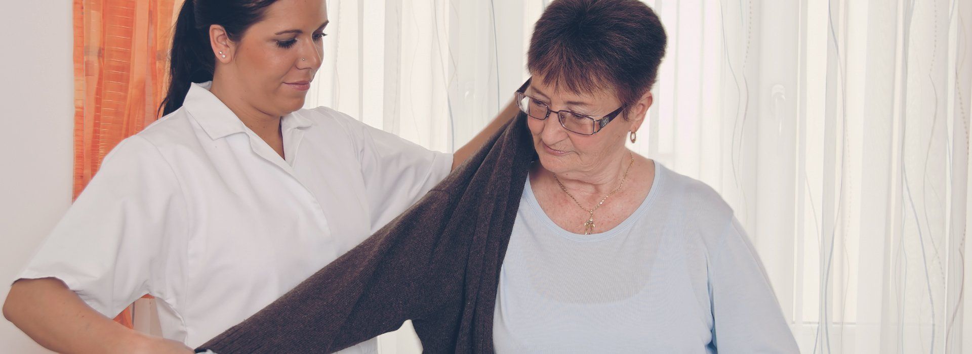 A carer dressing up the elderly