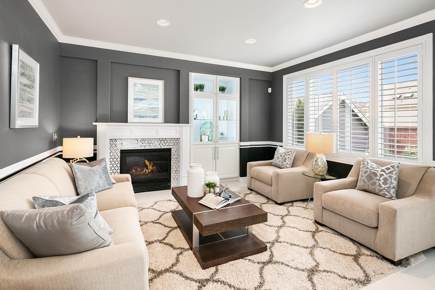 Bright living room with beige sofas, fireplace, gray walls, and large windows with white shutters