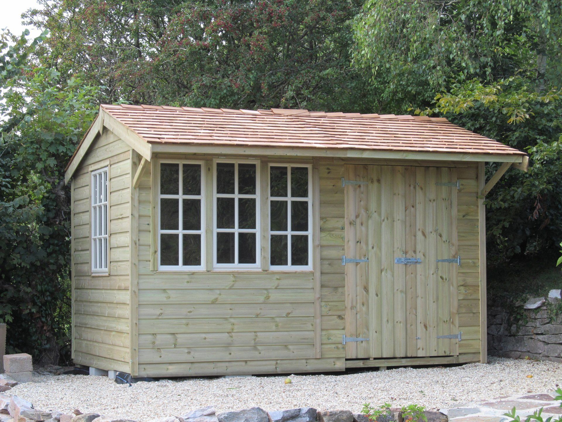 Cabin shed with triple painted windows and large double doors as well as red tiled roof