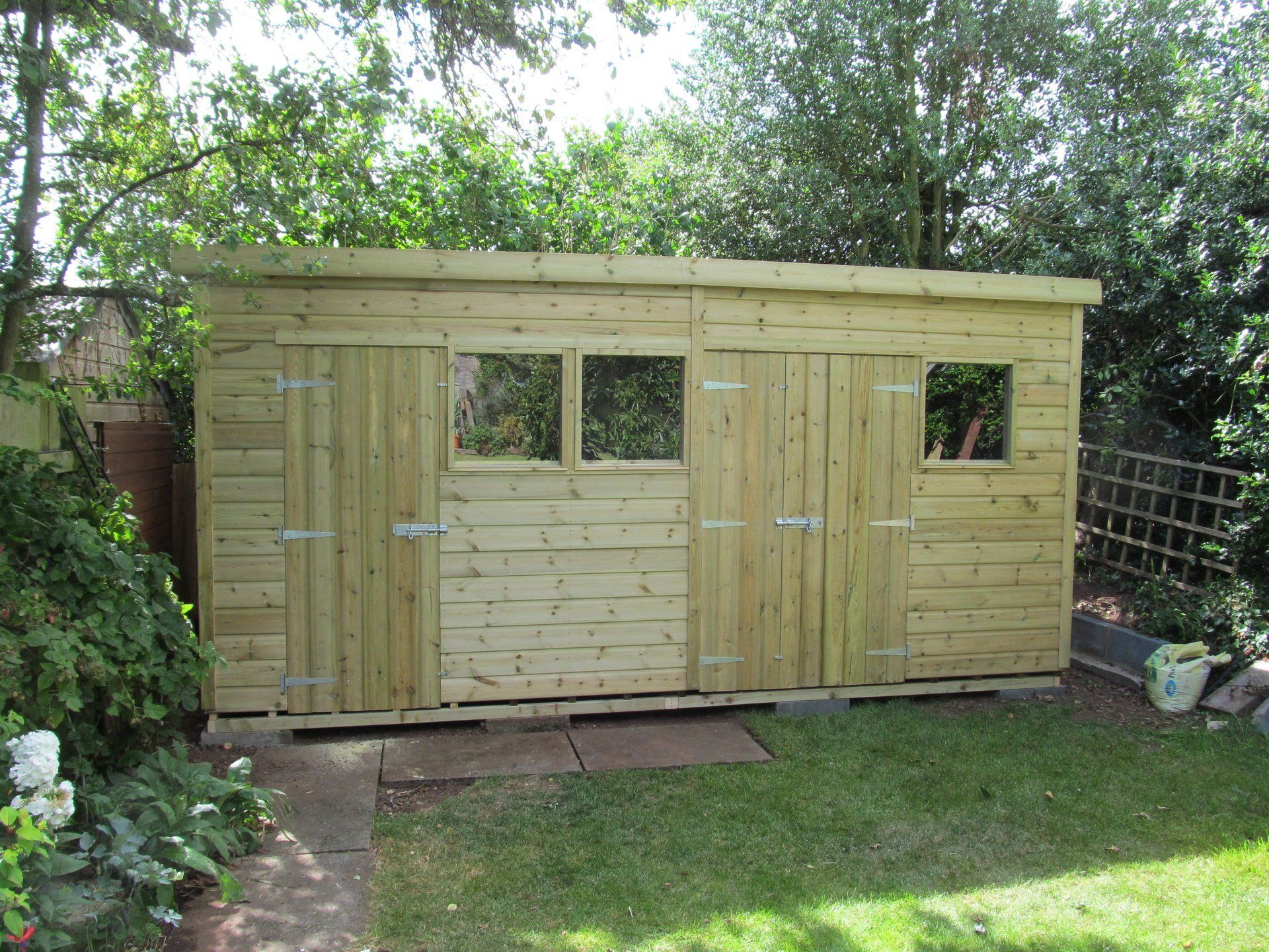 Large workshop shed with two doors and three windows and a sloping roof