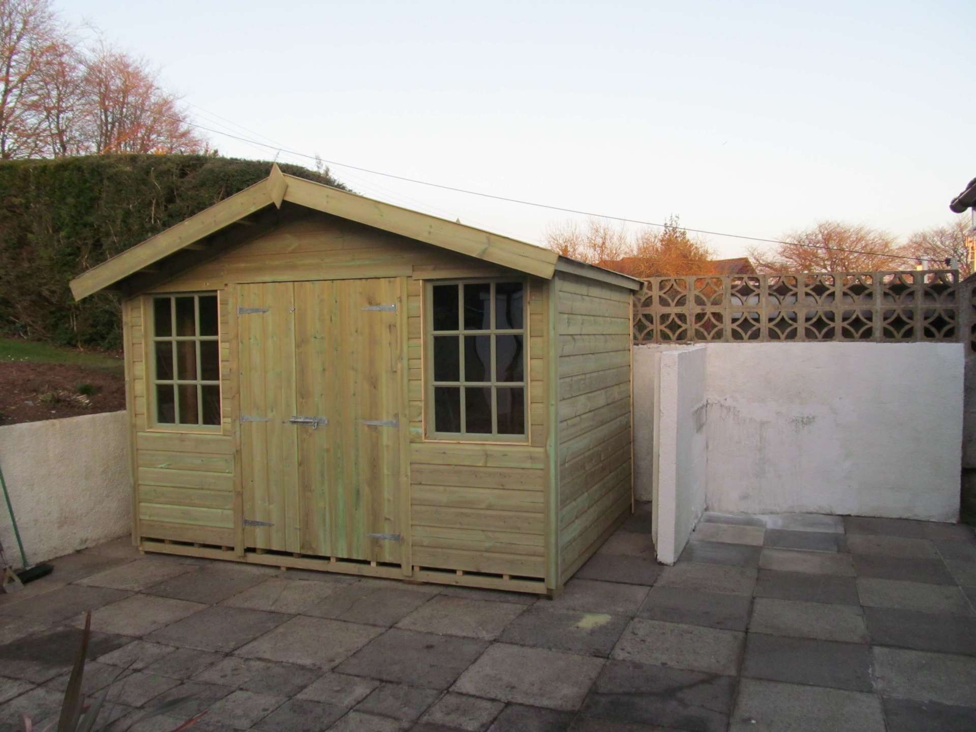 Large Exeter Cabin shed with door to the middle and painted windows on each side