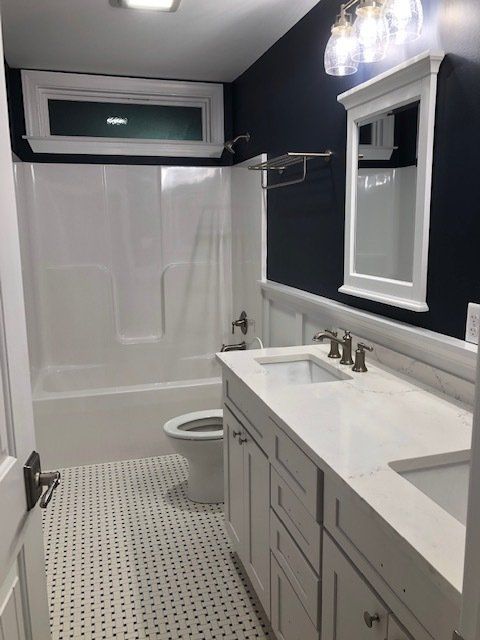 A bathroom with two sinks, toilet, and bath tub.