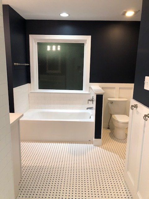 A bathroom with a tub a toilet and a window