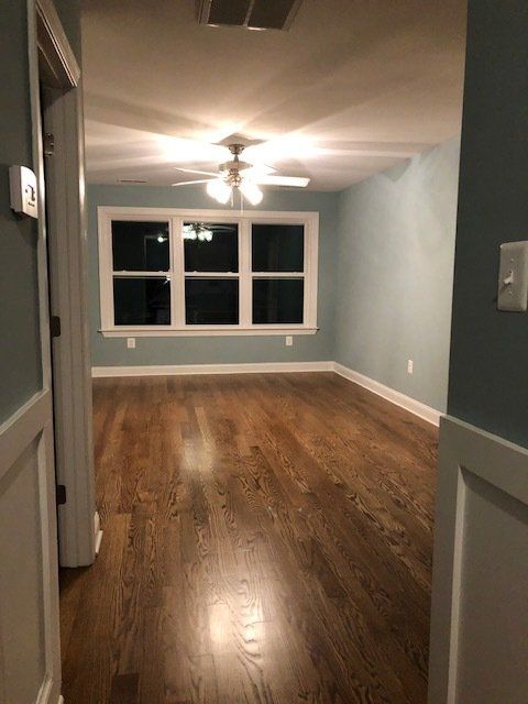 An empty room with hardwood floors and a ceiling fan.