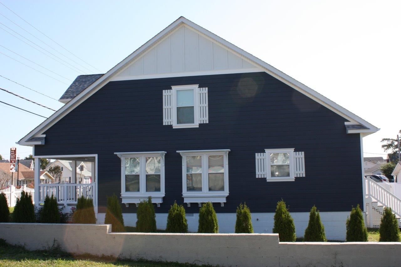 A grey house with white shutters on the windows