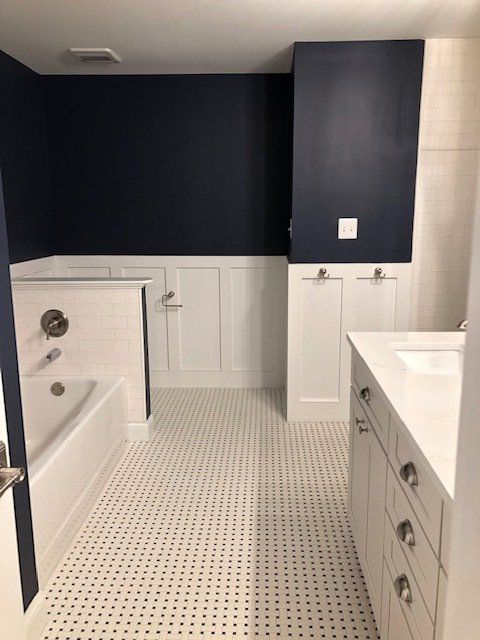 A remodeled bathroom with dark gray walls and white cabinets