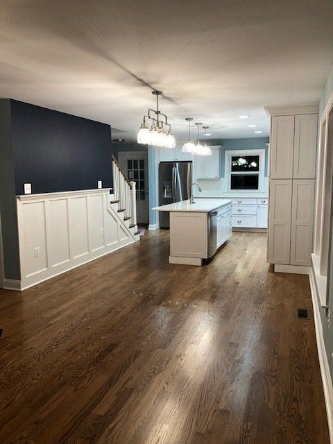A remodeled kitchen with hardwood floors and white cabinets and an island