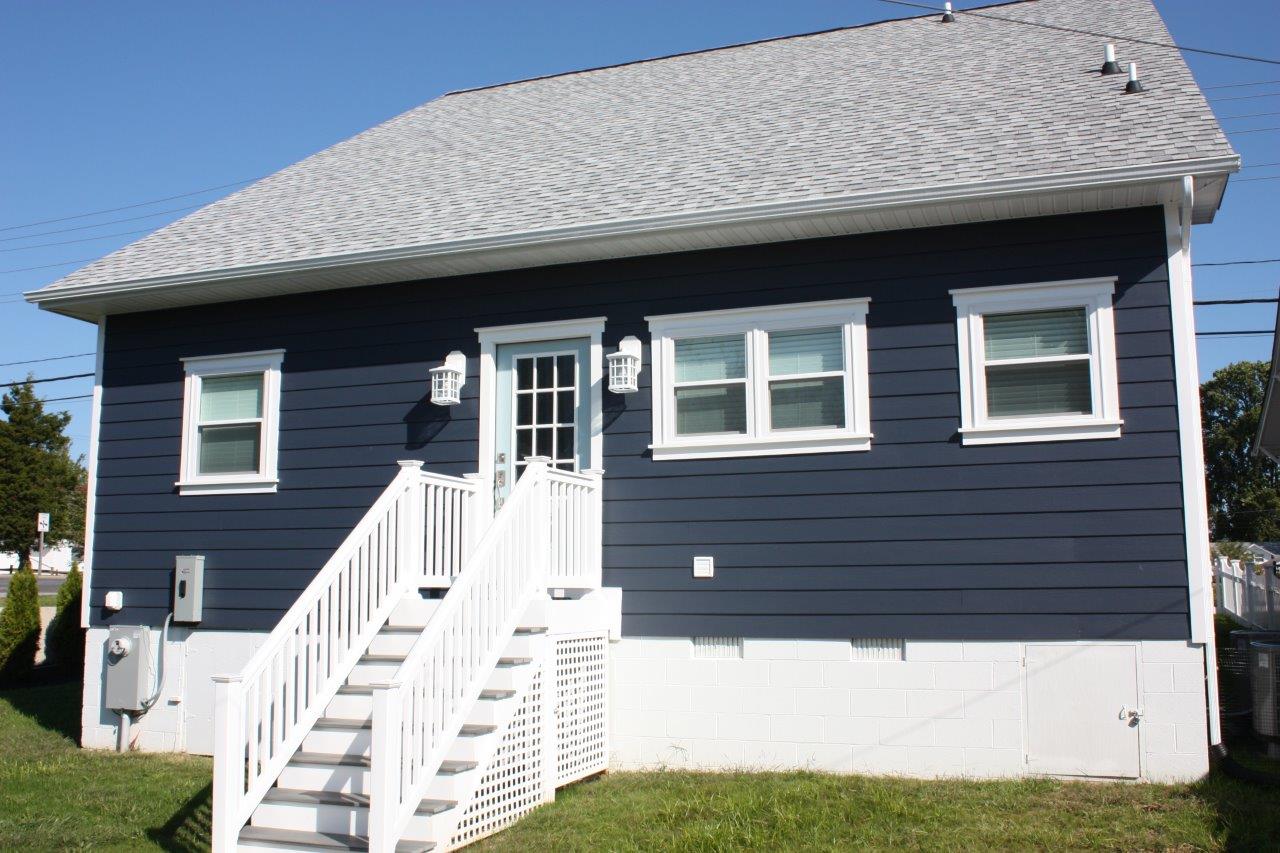 A dark gray house with white stairs leading up to it
