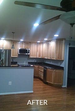After renovation of a  kitchen with wooden cabinets , stainless steel appliances , and a ceiling fan.