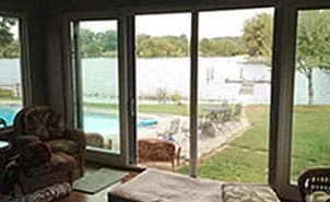 A living room with a view of ariver and a swimming pool.