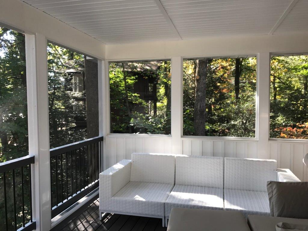 A screened in porch with a white couch and lots of windows