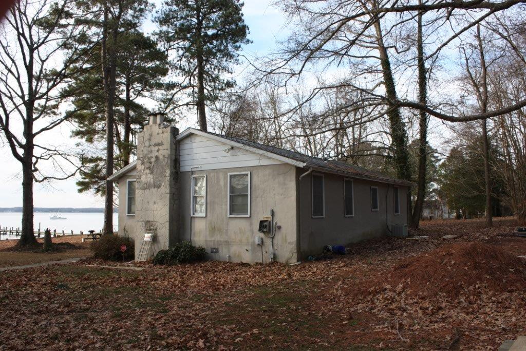 An old house with pine trees and water view.