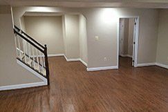 A finished basement with hardwood floors and stairs.