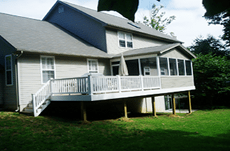 A house with a screened in porch and a large deck