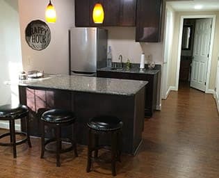 A kitchen with a large island and bar stools and a refrigerator.