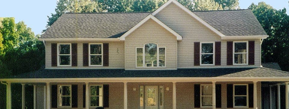 A large 2-story house with windows and shitters.