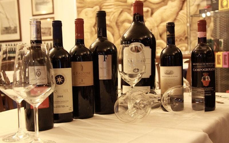 Diverse bottiglie di vino e bicchieri su un tavolo con una tovaglia bianca.