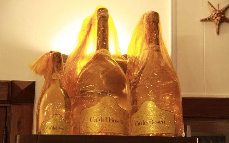 Due gigantesche bottiglie di champagne avvolte in carta, illuminate da dietro, con una stella marina sul muro.