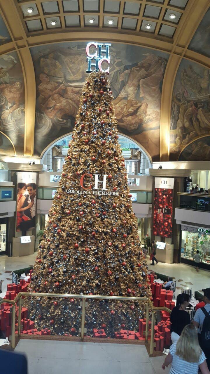 Un alto árbol de Navidad decorado en un gran atrio interior con gente cerca.