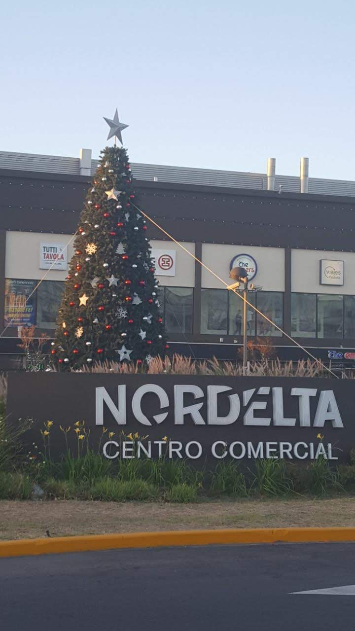 Árbol de Navidad frente al edificio Nordelta Centro Comercial al anochecer.