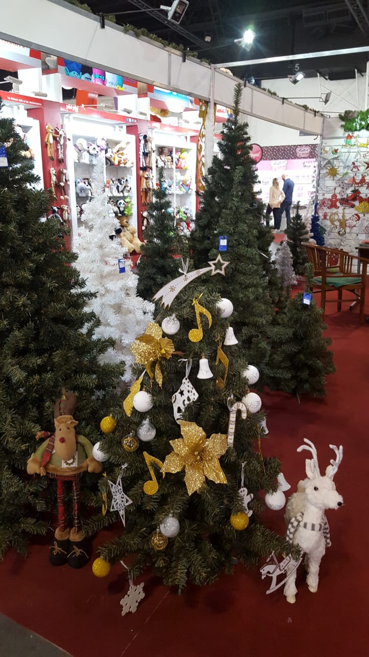 Árboles de Navidad decorados con adornos y figuras de renos en el escaparate de una tienda navideña.
